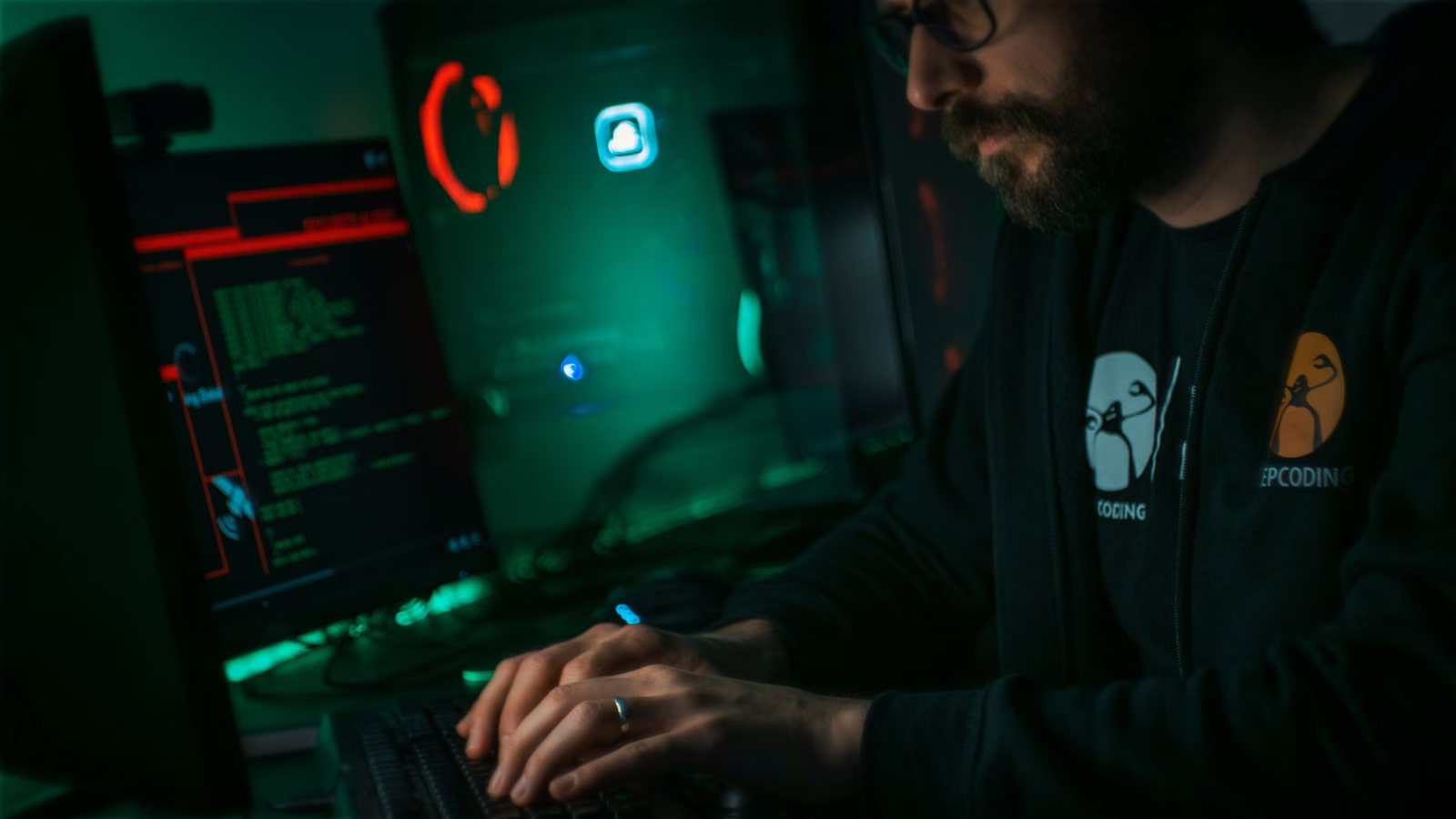 Security analyst typing in a dark room lit by green and red monitor displays