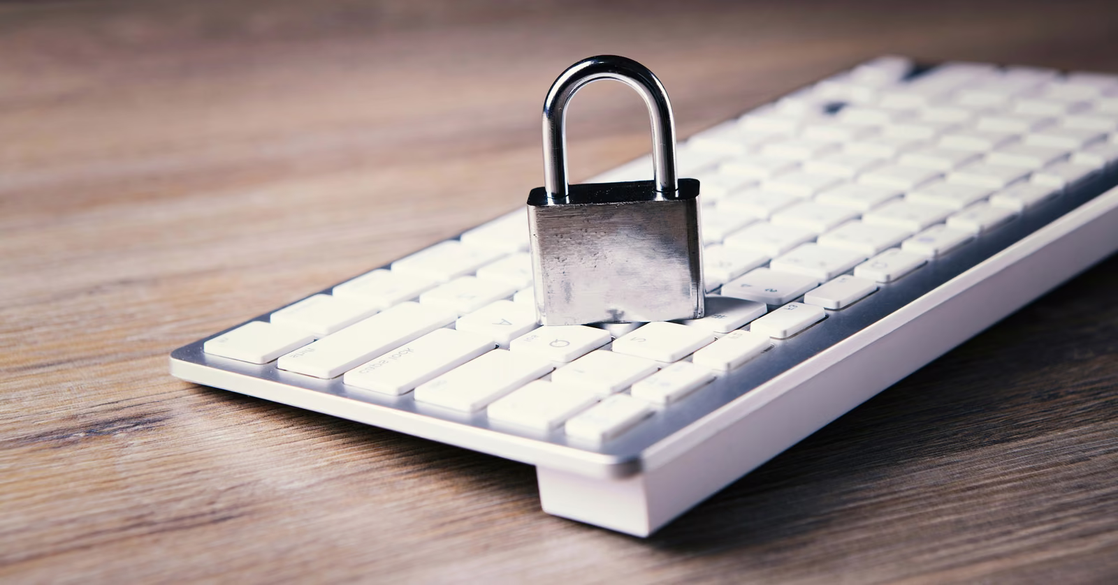 Metal padlock sitting on a white computer keyboard, representing data security